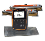A Gallagher TW-1 electronic Cattle and livestock scale indicator with a black and orange casing stands in front of loadbars on a white background. A textured gray platform is placed beneath the device.