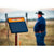 Gallagher S120 Solar fence charger on a post with a person in a cowboy hat in the background